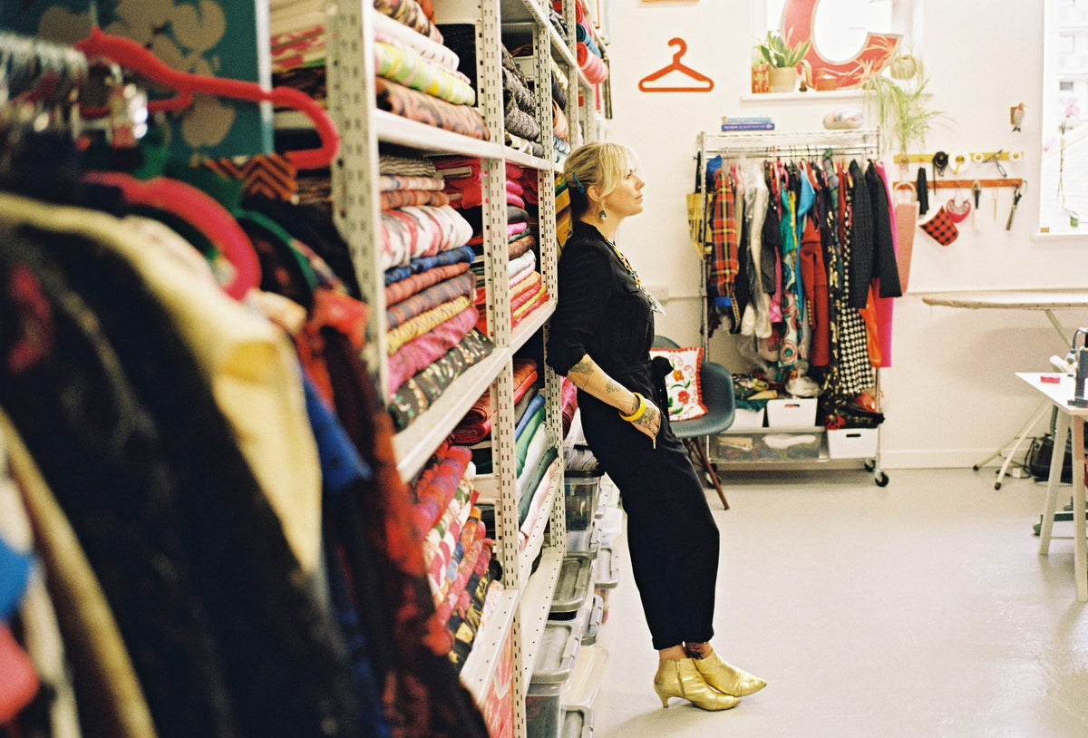 Holly Campbell leaning against shelves of fabric rolls in the Totty Rocks studio