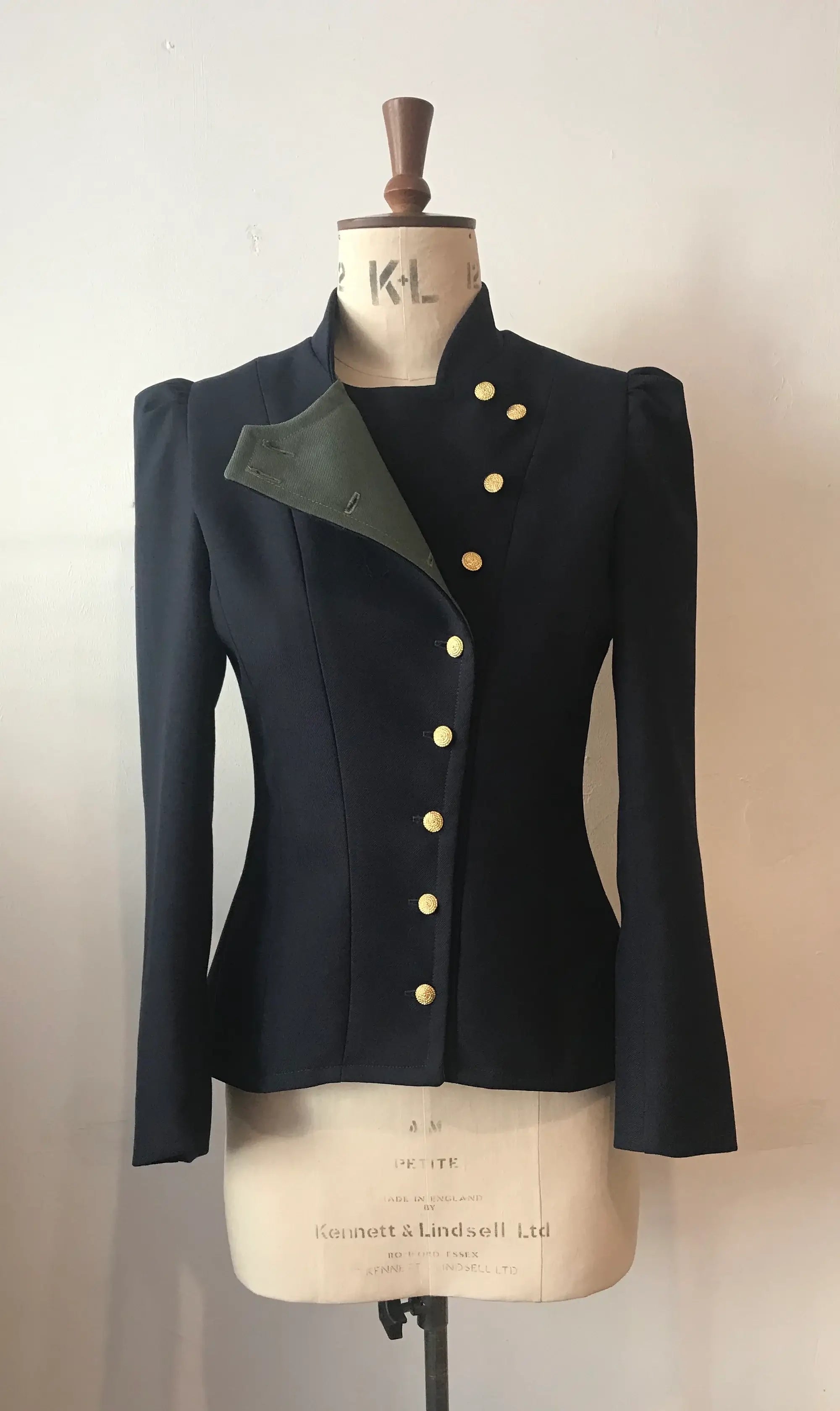 A 2-tone fencing jacket displayed on a mannequin, with contrasting front-facing panels in a different color and gold buttons.
