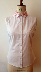 A tailored white shirt with a double bib front and hand-printed ponies on the collar and cuffs displayed on a mannequin.
