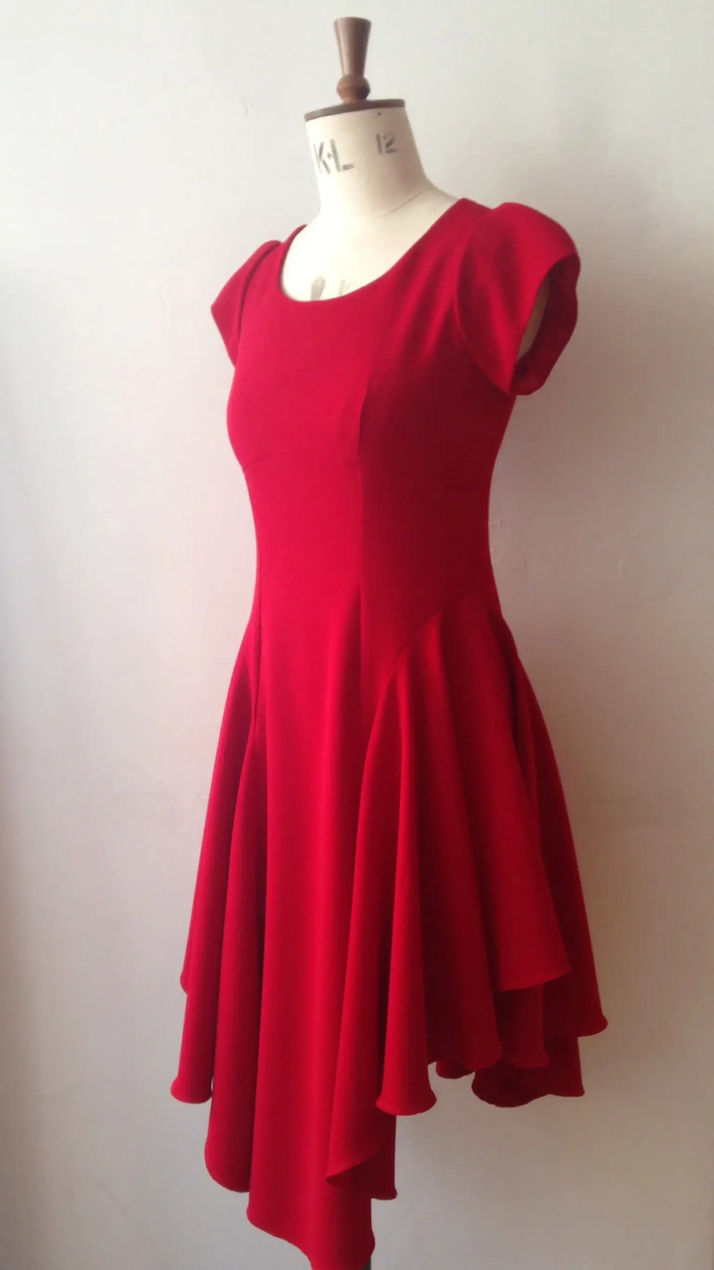A red sleeveless knee-length dress with a flowing hemline displayed on a mannequin.