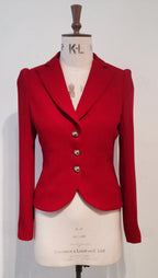 A red jacket with a 3-button closure and triple frill detail at the back displayed on a mannequin.