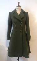 A double-breasted, flared green coat with antique brass-effect buttons and a soft, rounded collar, displayed on a mannequin.