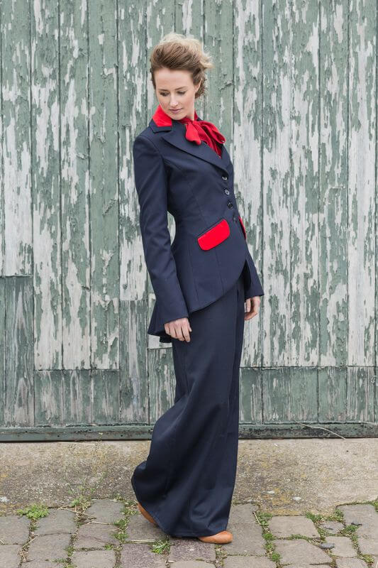 A woman modeling a Miss Agnes Swing Jacket with a vintage feel, featuring a navy blue color, velvet detailing, and a long-line design.