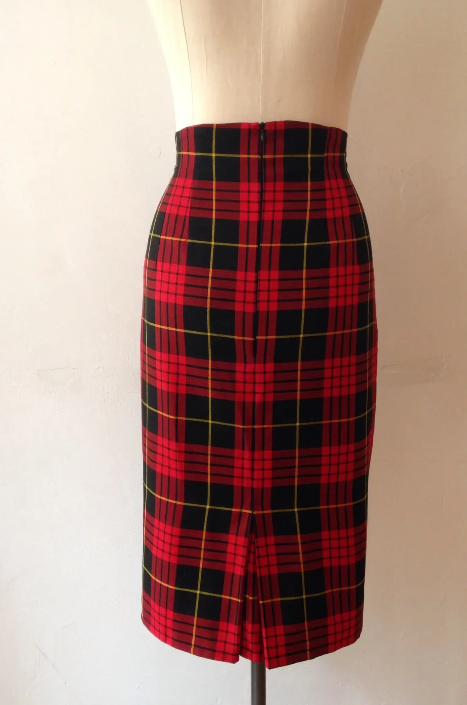 A high waisted, knee-length pencil skirt with a red and black tartan pattern, displayed on a mannequin.