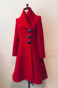 A red swing coat with a shawl collar and three large buttons, displayed on a mannequin against a plain background.