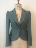 A Tweed Coachwoman Jacket displayed on a mannequin, in Nordic blue, with pleated side panels and a single-button closure.