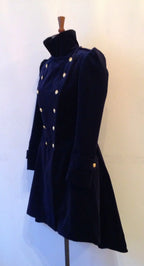 A navy velvet frock coat with double-breasted design and brass dome buttons, displayed on a mannequin.